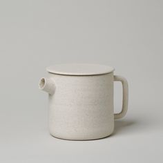 a white ceramic cup with a handle on a gray background, sitting in front of the camera