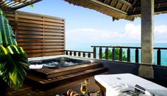 a hot tub sitting on top of a wooden deck next to the ocean with fruit