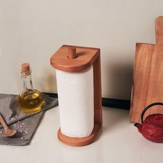 a bottle of oil next to a wooden holder with a roll of toilet paper on it