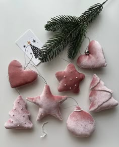 pink ornaments are hanging from a tree branch on a white surface with a christmas card in the background