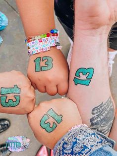 three people holding hands with numbers painted on their wrists and wristbands in the shape of letters