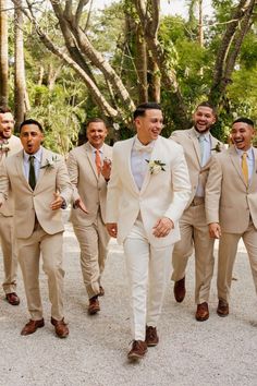 a group of men in tan suits and ties walking down the street with each other