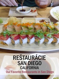 there are many different types of sushi on this plate and in the background is a bowl of dipping sauce