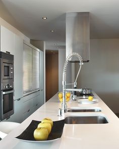 a modern kitchen with stainless steel appliances and white counter tops, along with yellow fruit