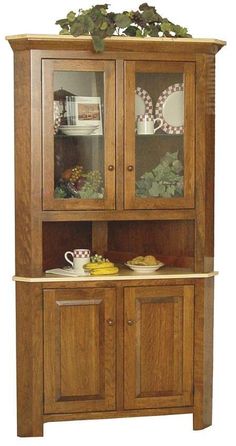 a wooden china cabinet with glass doors and drawers on the top, holding plates and cups