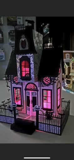 a doll house is lit up with pink lights