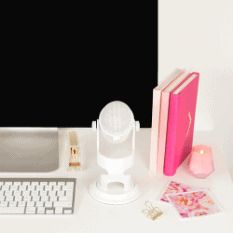 a white desk with a computer, books and other items on it in front of a black screen