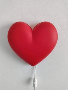 a red heart shaped object hanging on the side of a wall with headphones attached to it