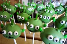 some green apples with googly eyes are on a stick in the shape of an apple