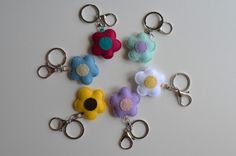 four different colored flowers are on the keychains with one being held by a pair of scissors