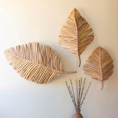 three pieces of art made out of sticks and branches on a wall next to a vase