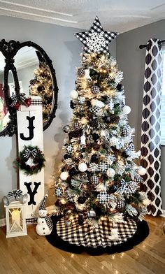 a decorated christmas tree in the corner of a living room with black and white decor