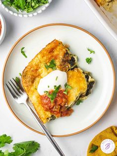 a white plate topped with an omelet covered in toppings and a fork