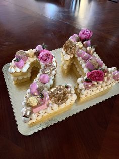 a cake shaped like the letter e with flowers on it sitting on top of a wooden table