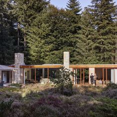 two people standing in front of a house surrounded by trees