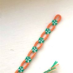 an orange and green beaded bracelet with a tassel on it's end