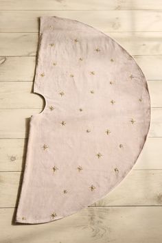 a pink blanket with gold stars is laying on a white wooden floor next to a pair of scissors