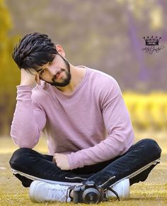 a man sitting on the ground with his head in his hands while holding his hand to his ear