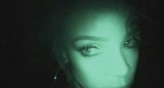 a woman's face in the dark with green light coming from behind her head