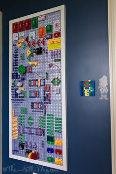 a blue wall with a lego map hanging on it's side next to a white door