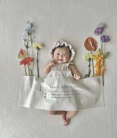 a baby doll laying on top of a white sheet with flowers around it and the words wild birthday