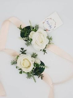 two white roses and greenery tied together