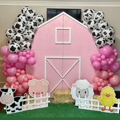 a pink barn with balloons and farm animals on the front door is set up for a birthday party