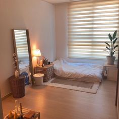 a bedroom with a bed, mirror and lamp on the floor in front of it