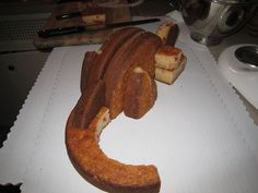 a cake shaped like a snake on top of a white paper cutting board next to a knife