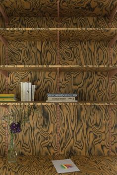 a vase with flowers and books on a shelf made out of tiger print wood planks