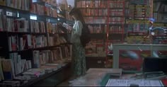 a woman standing in front of a bookshelf filled with lots of book's