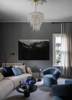 a living room filled with furniture and a chandelier hanging over the top of it