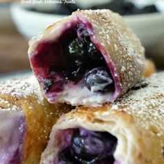 blueberry cream cheese - egg rolls are stacked on top of each other with powdered sugar