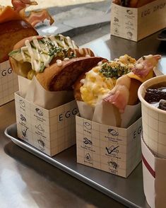 three different types of sandwiches on trays next to cups with condiments in them