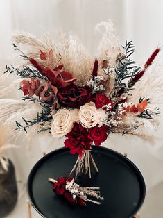 a vase filled with flowers and feathers on top of a table