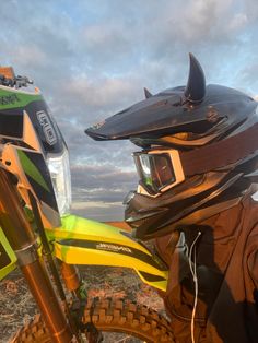 a person wearing a helmet and goggles standing next to a dirt bike