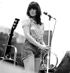 a woman standing in front of a microphone on top of a stage with other equipment behind her