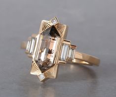 Named after Hilma AF Klint. This new setting was a dream ring we had been envisioning in the back of our minds for some time. For our first ring we chose this lovely 1.74ct Champagne Rosecut Elongated Hexagon Diamond and we accented it with some good size diamond baguettes and a few princess diamonds on the top and b Saphire Engament Ring Bezel, Unique Witchy Engagement Rings, Art Deco Fine Jewelry, Art Deco Ring Vintage, Architectural Engagement Ring, Gold And Black Engagement Ring, Artemer Engagement Rings, Elongated Hexagon Ring, Dream Engagement Rings Gold