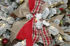 a close up of a christmas tree with snow flakes and red ribbon on it