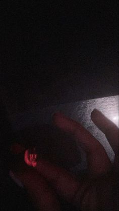 a person laying down in the dark with their hand on top of a computer mouse