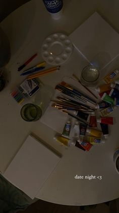 the table is covered with art supplies such as paint, pencils and paper