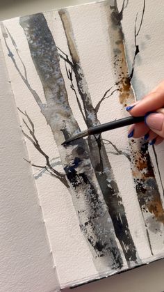 a person is painting trees with watercolors on paper