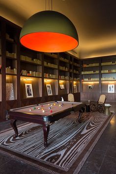 a pool table in the middle of a room with many bookshelves and chairs