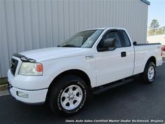 a white pickup truck parked in front of a metal building on the side of the road