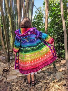 a woman standing in the woods wearing a colorful shawl