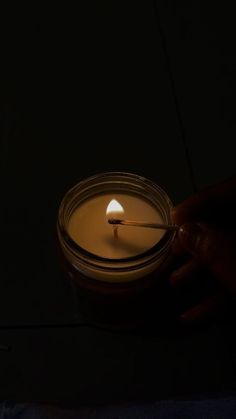 a person holding a lit candle in the dark with their hand on top of it