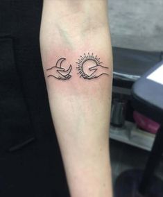 a woman's arm with two hands holding the sun and moon tattoo on it