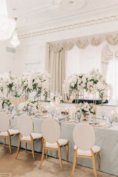 there are many chairs and tables set up for a formal function with white flowers on the table