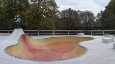 a skateboard ramp with a statue in the center and trees behind it on a cloudy day