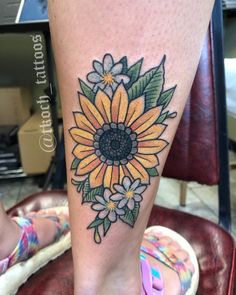 a woman's foot with a sunflower tattoo on the side of her leg